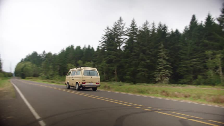 A van driving down a road next to a field