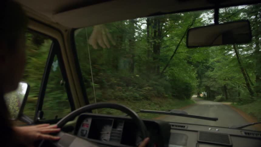 Woman drives along road past woods and driveways leading to homes placed far apart