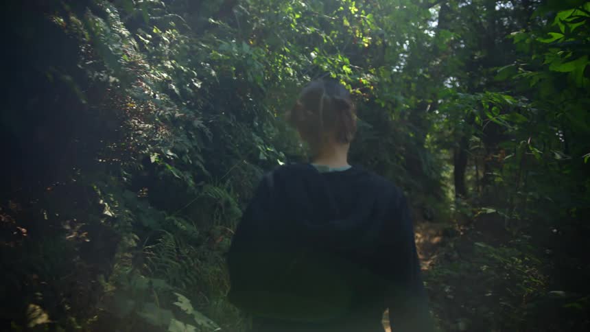 A woman is walking through a forest during the day