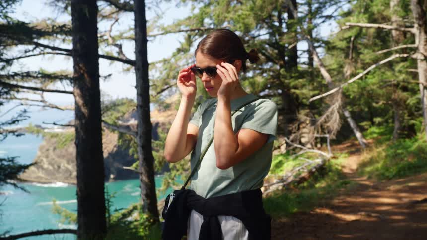A woman puts on her sunglasses on the trail