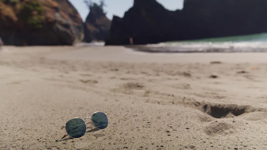 A pair of sunglasses on the beach