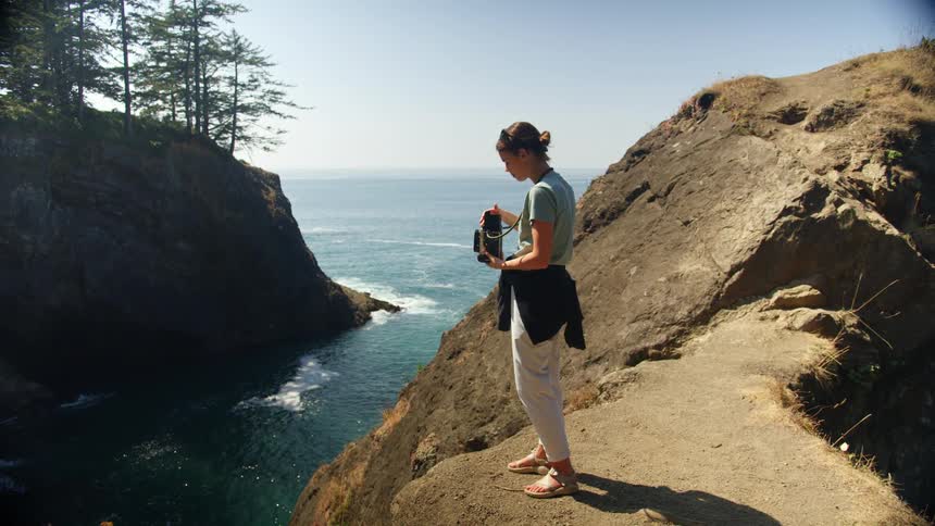 A young girl takes a picture of the water with a vintage camera