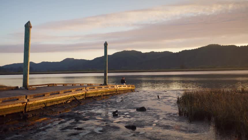 A person sitting on the dock looking out at the water
