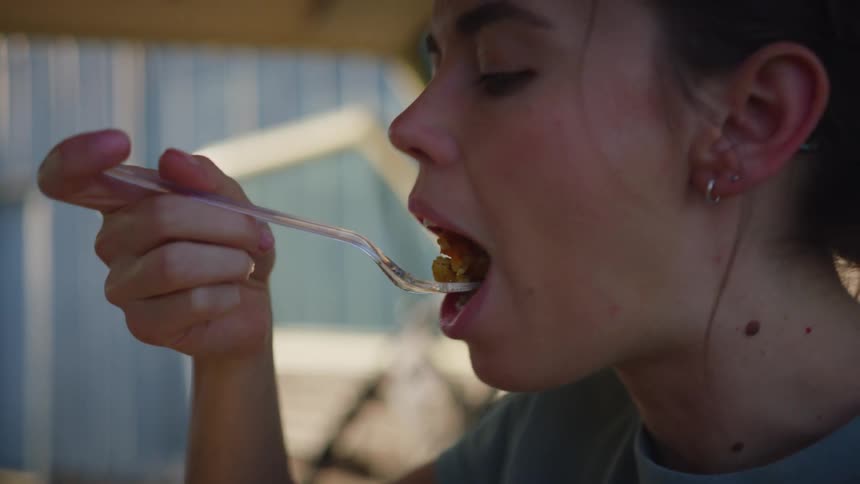 A young woman sitting in her vehicle eats a meal