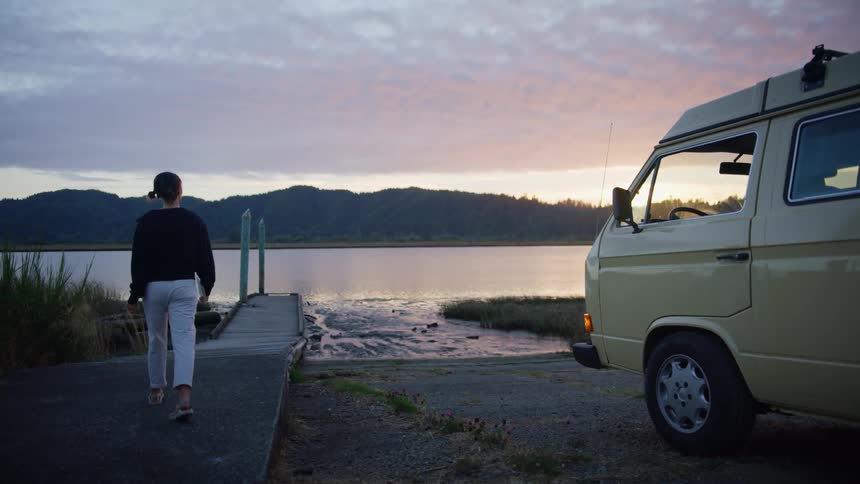 A person walks from an old van to a pier on the lake