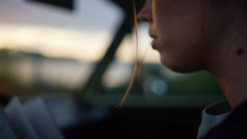 A woman is sitting in a car and reading a book