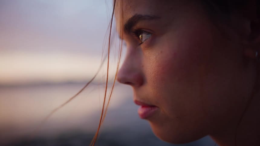 Side view of a woman with brown hair rises her head at sunset