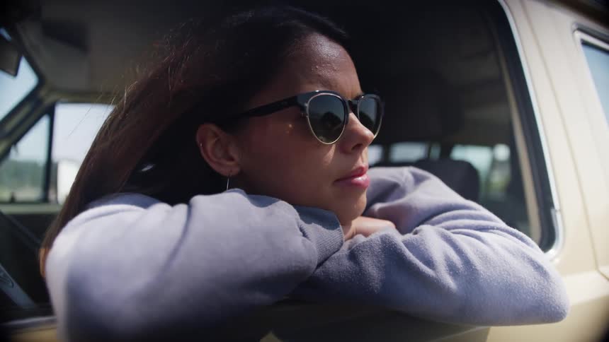 A woman is looking out a window of a driving car