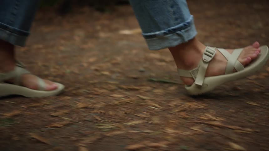 A woman is walking outdoors while wearing sandals