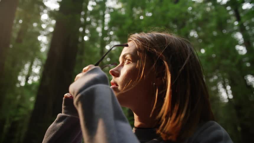 A woman is walking in the woods during the day