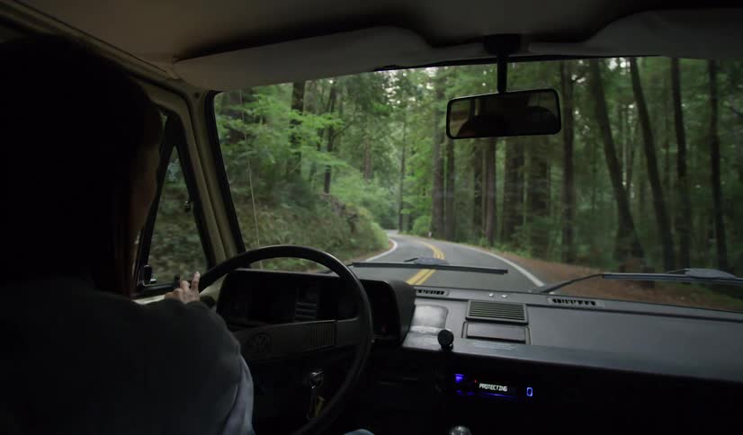 Woman drives on a highway through the forest