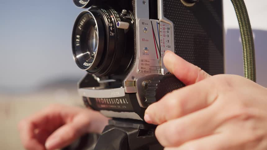 A photographer turning a dial on a camera outdoors
