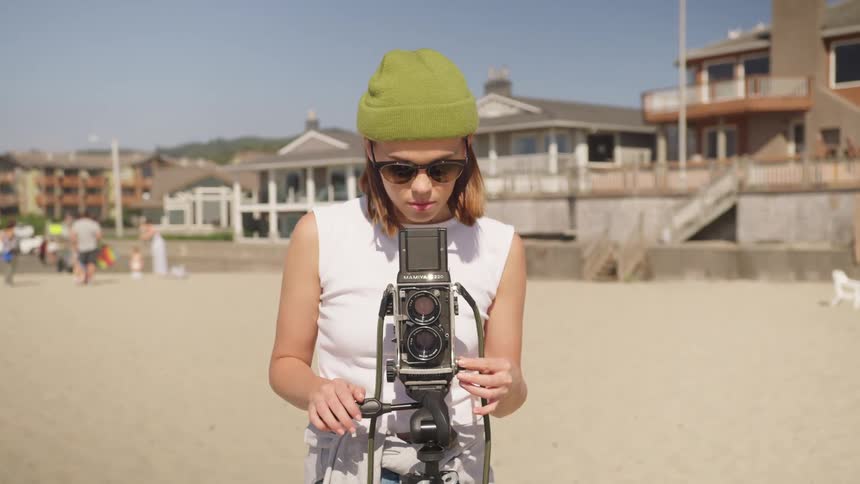 A teenage girl takes photos on a beach