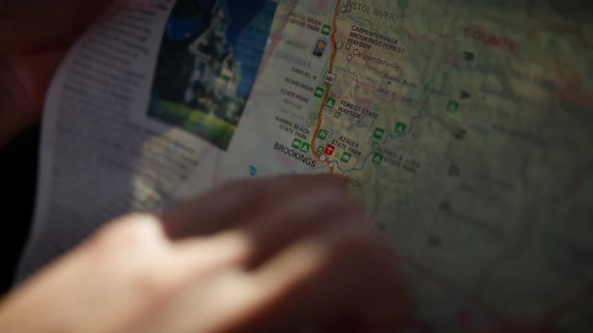 A hand is pointing to a map and tracing a route up the map with a finger