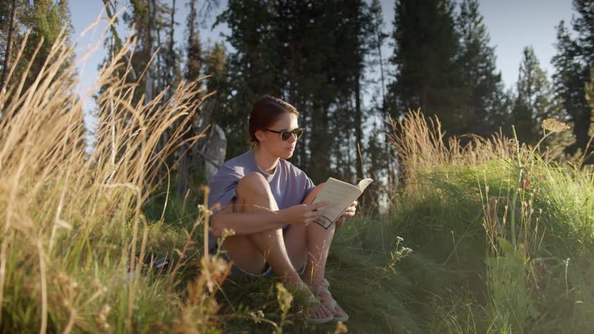 A woman is reading a book on the hill