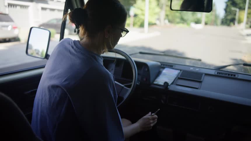 A young woman sits in the driver seat of a large vehicle and puts the keys in the ignition