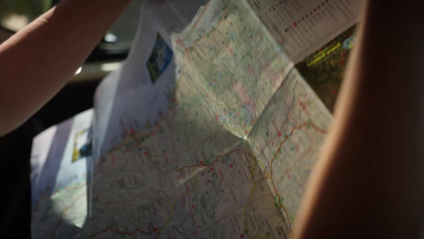 A woman in a car opens up a map and looks at it