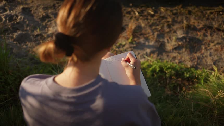 A woman is writing in her notebook outside
