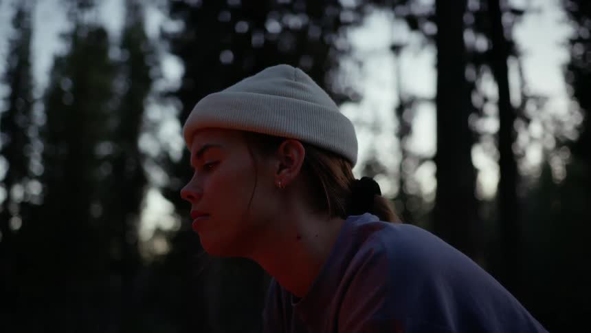 A woman is looking into the campfire