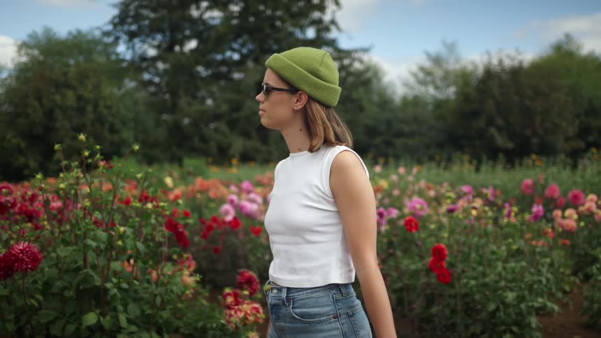 A woman is walking outdoors by the flowers