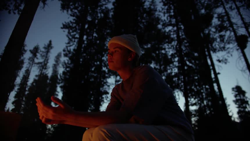 A woman is warming up by the campfire
