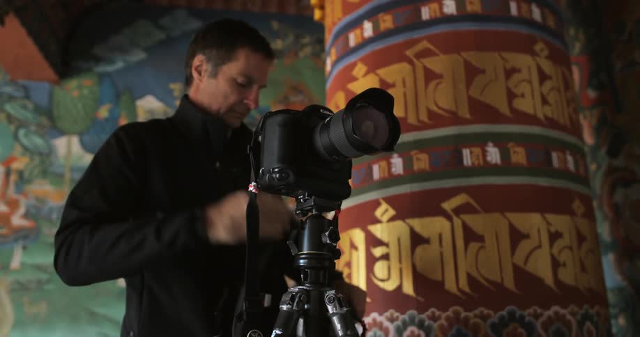A man places and sets up a camera on a tripod