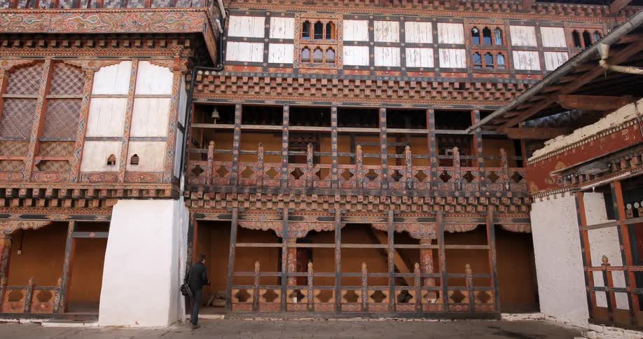 A man walks quickly down a street next to an ornate building