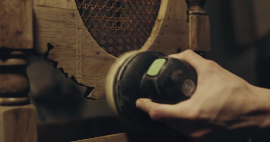 Person buffs wooden furniture with a power tool