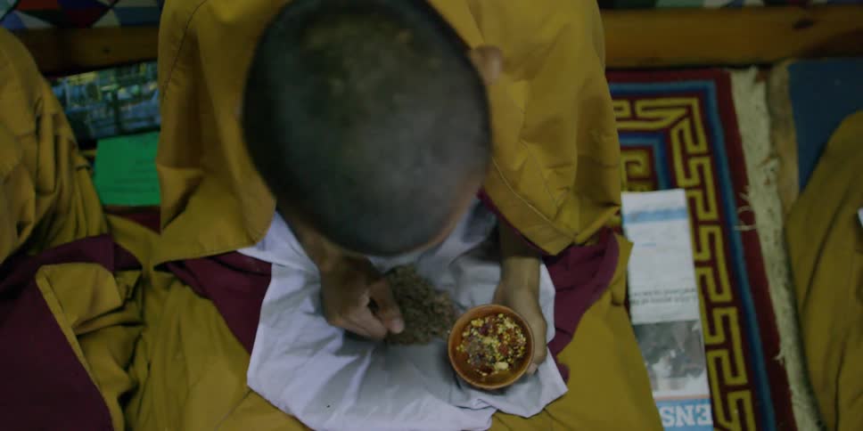 A man is sitting and has a bowl in his hand