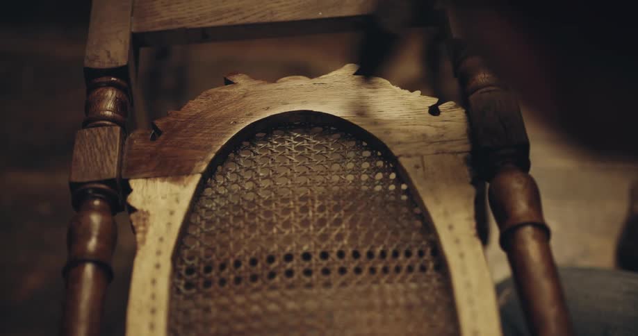 Person stains wooden chair with brush