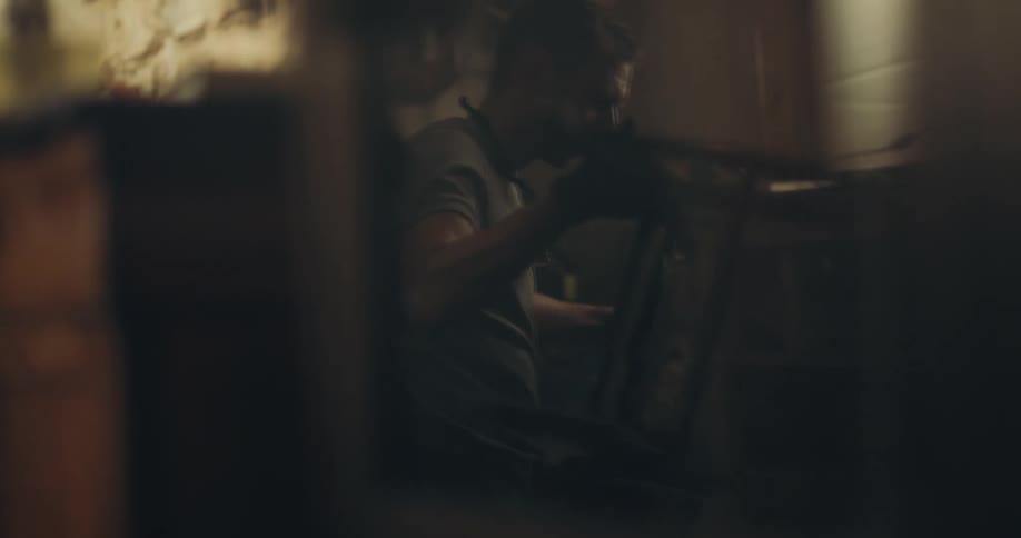A man with gloves in a workshop working on a wooden chair