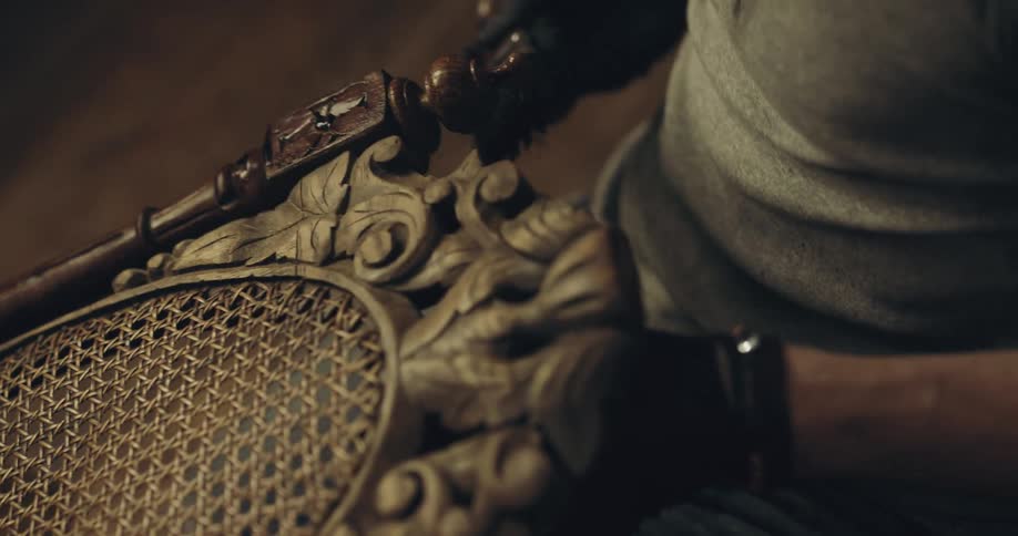 A man applies wood stain to a chair in a furniture store