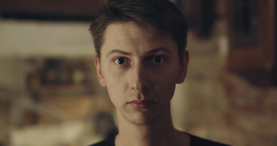 A young white male looks up into a camera with a steady gaze