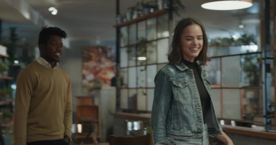 A man talks with a smiling woman as they take a seat together in a restaurant