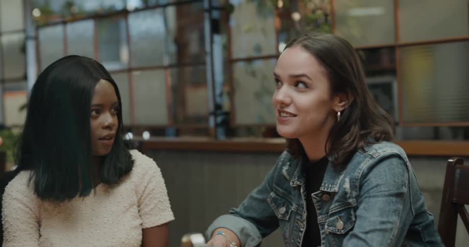 Man helps woman remove jacket before she sits as they join friends in pub