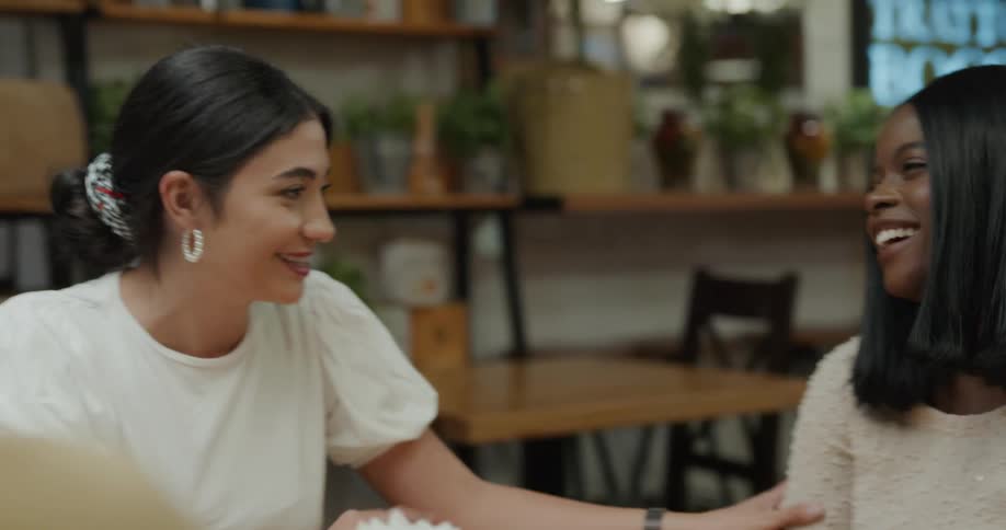 A group of women sitting at a table talks to each other and laugh together in a cafeteria