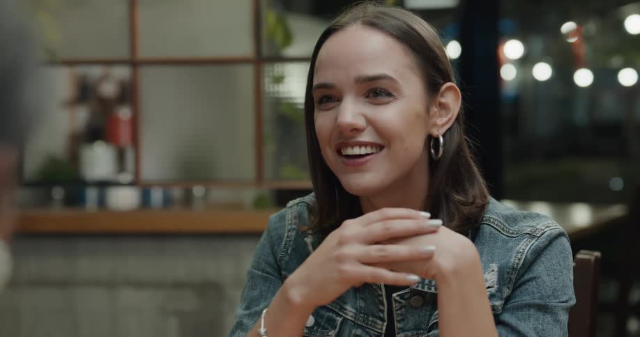 Two women sit and talk and laugh in a restaurant