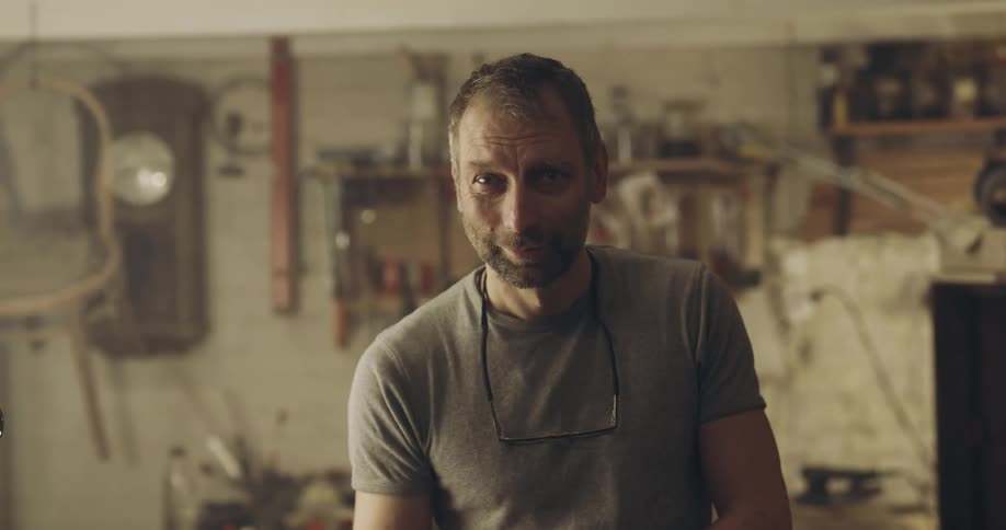 A man in his garage looks up and smiles for a photo