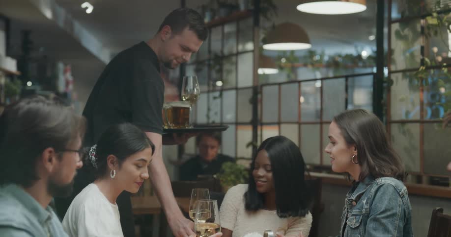 People sitting at the table are being served drinks