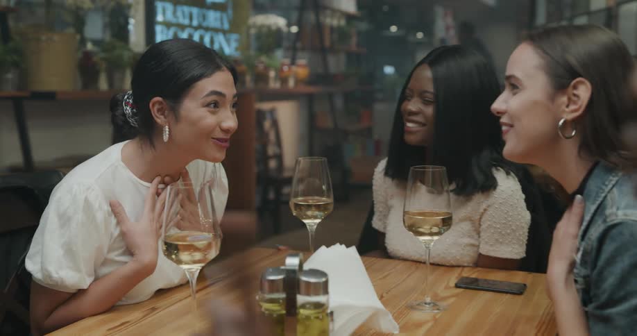Friends sits around table at pub with drinks laughing and talking