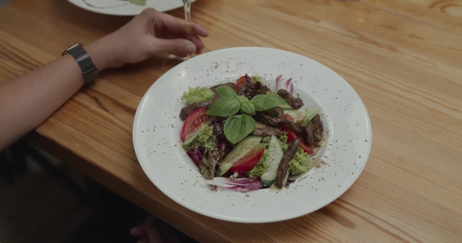 A salad being placed in front of a customer in a restaurant