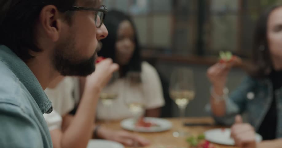 Two women and a man sit in a restaurant and eat and talk