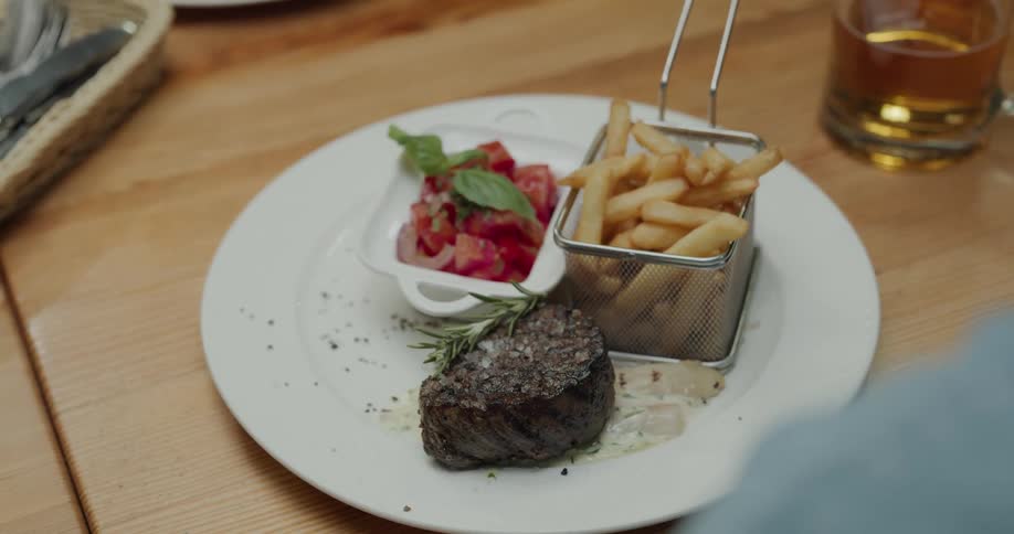 Server places dinner on wooden table in front of customer next to beer mug