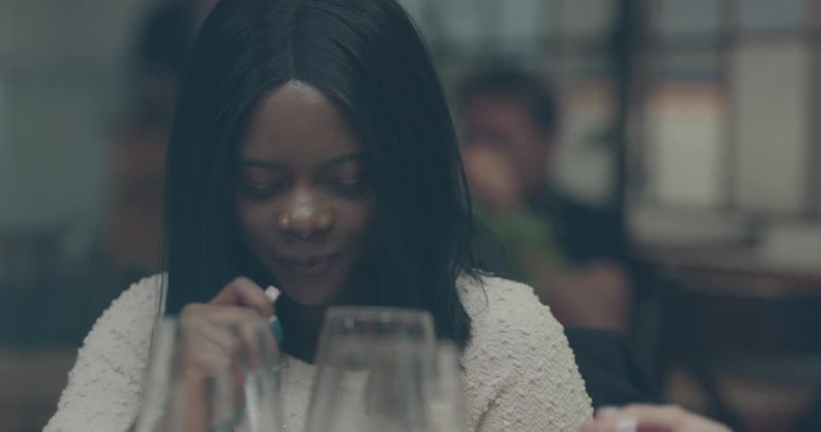Woman with straight hair sitting at the table eats food while laughing with her friends in the restaurant