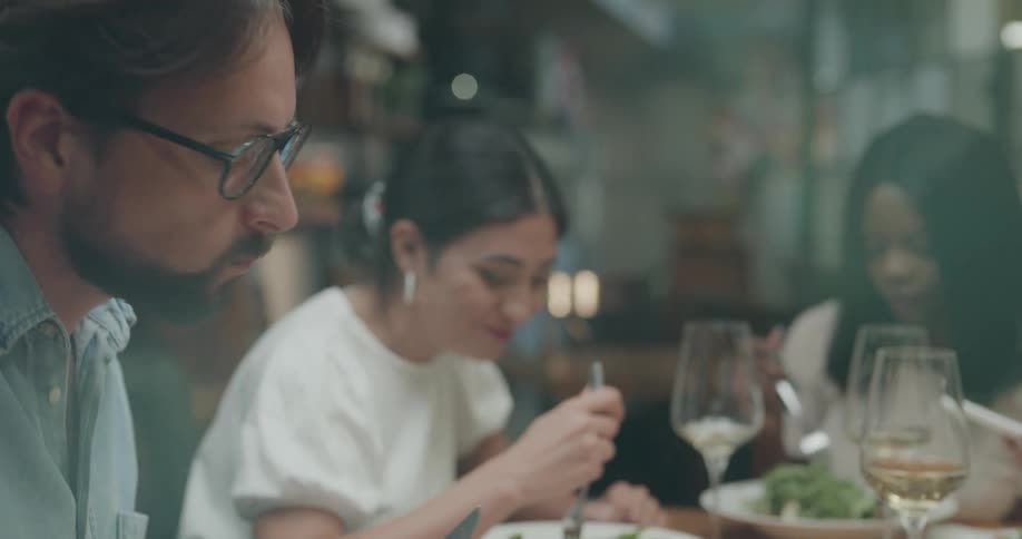 A group of people chat while eating and drinking together in a restaurant