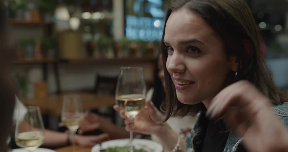 A group of people sit at a restaurant together drinking wine and beer with food bowls in front of them