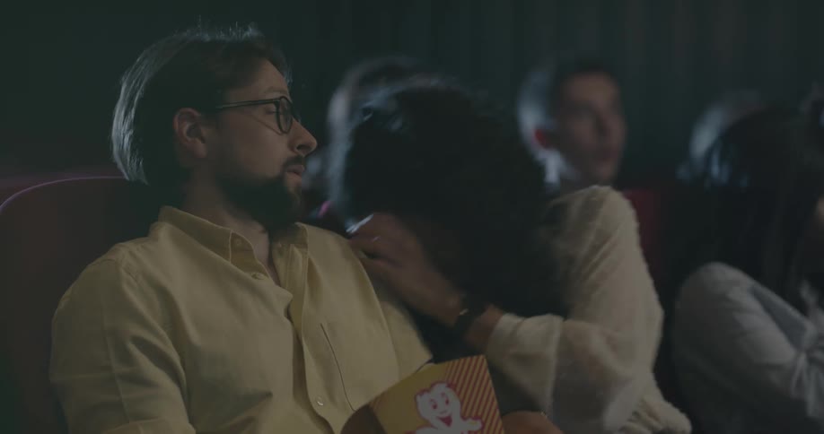 A woman watching a movie with her couple gets scared and covers her eyes