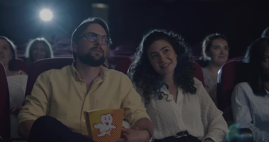 People laughing and eating popcorn in a movie theater