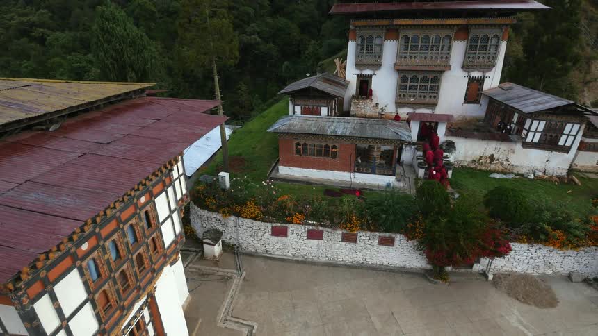Buddhist monks file through a gate and into a building