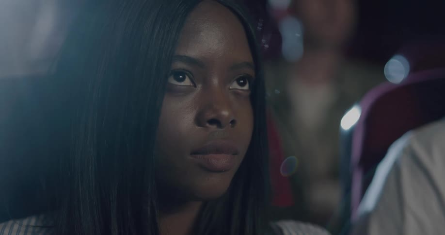 Woman with straight hair eats popcorn while watching a movie in the movie theater